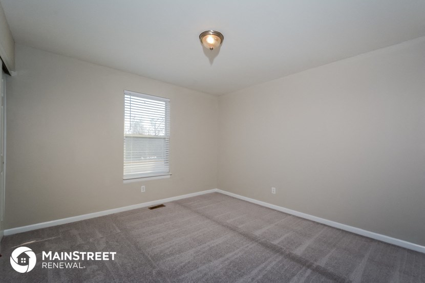 the spacious living room with carpeting and a window