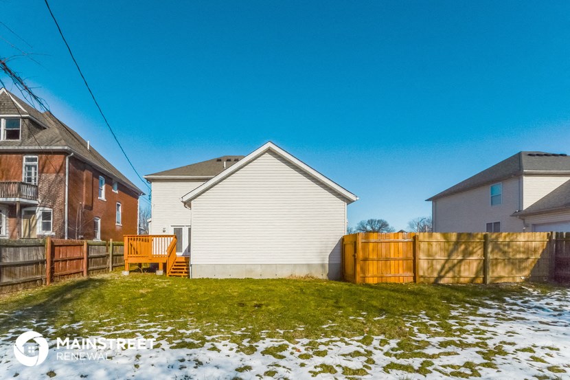 the backyard of a house with a fence and a yard with snow