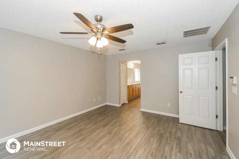 the living room and dining room of an apartment with a ceiling fan
