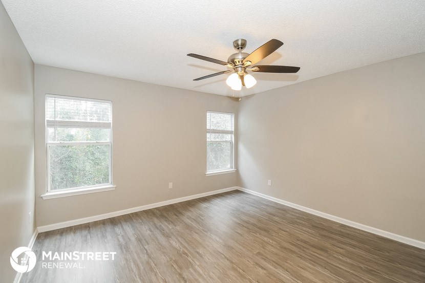 the spacious living room with ceiling fan and wood flooring