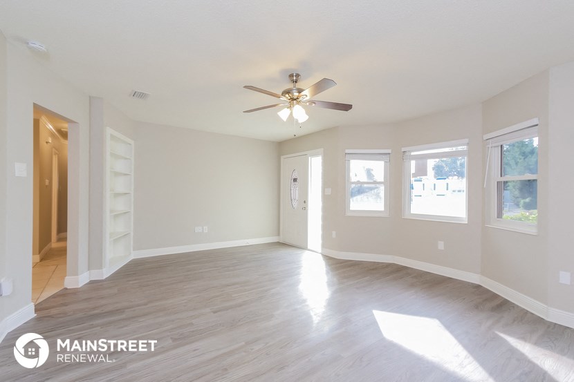 an empty living room with white walls and a ceiling fan