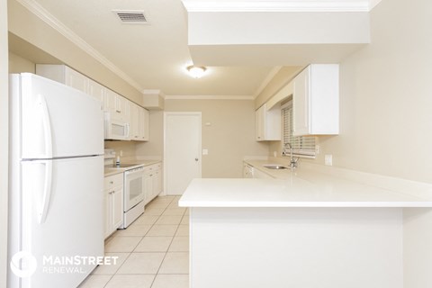a white kitchen with a white counter top and a refrigerator