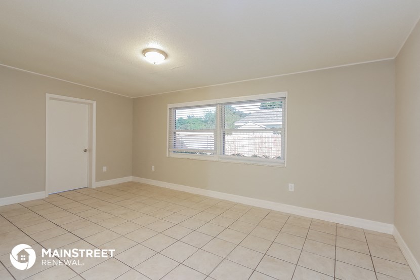 the living room of a house with a large window and a tiled floor