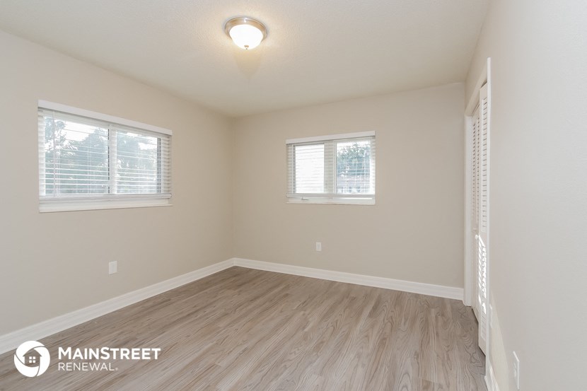 the spacious living room with hardwood flooring and two windows