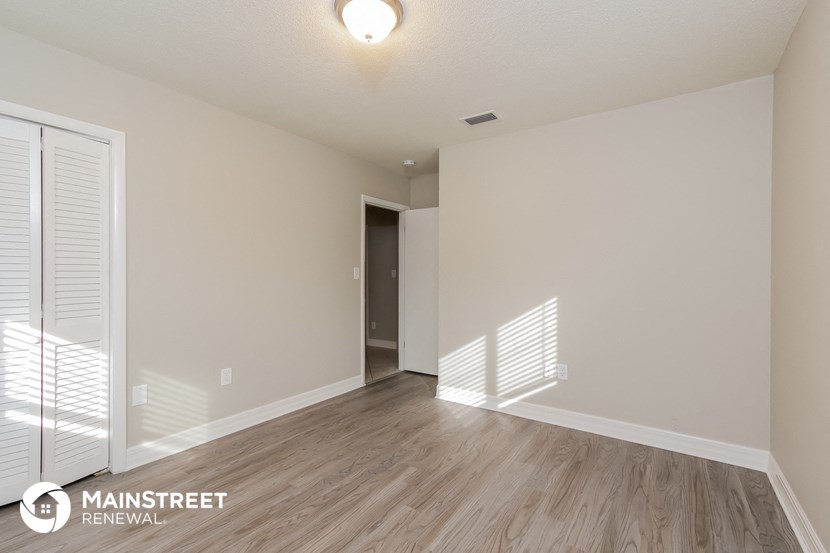 the spacious living room with wood flooring and white walls