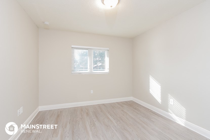 the spacious living room with wood flooring and a window