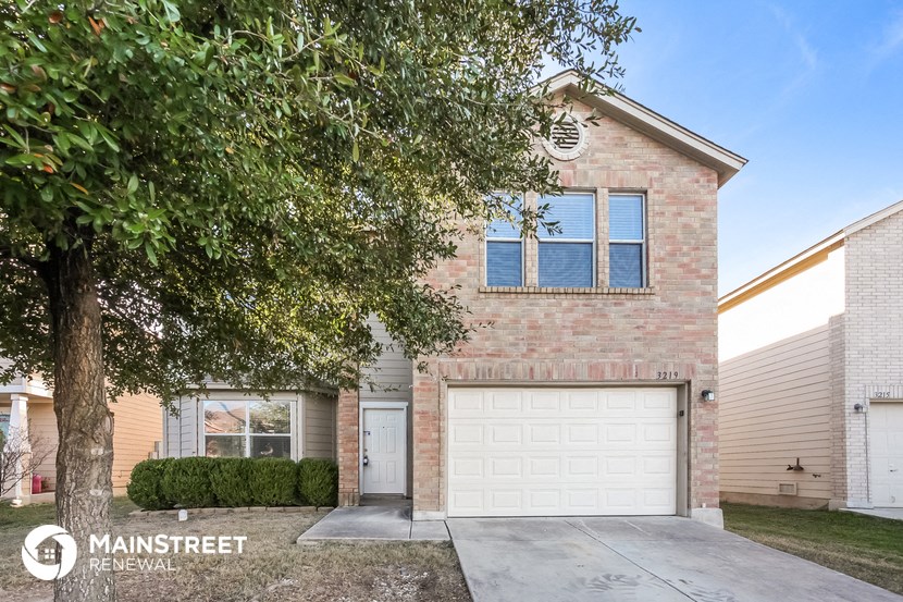 a brick house with a white garage door and a tree