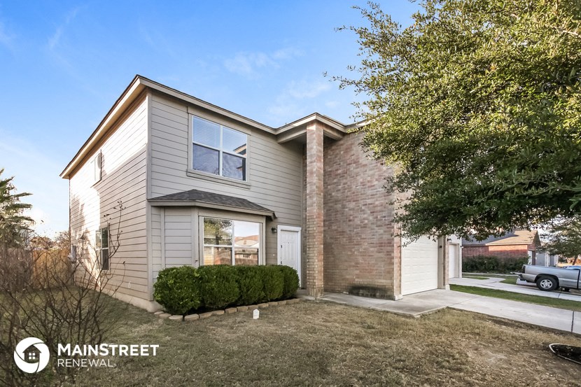 a white and brick house with a yard and a tree