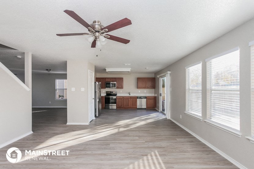 a living room with a ceiling fan and a kitchen