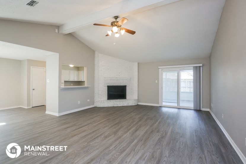 the spacious living room with fireplace and ceiling fan