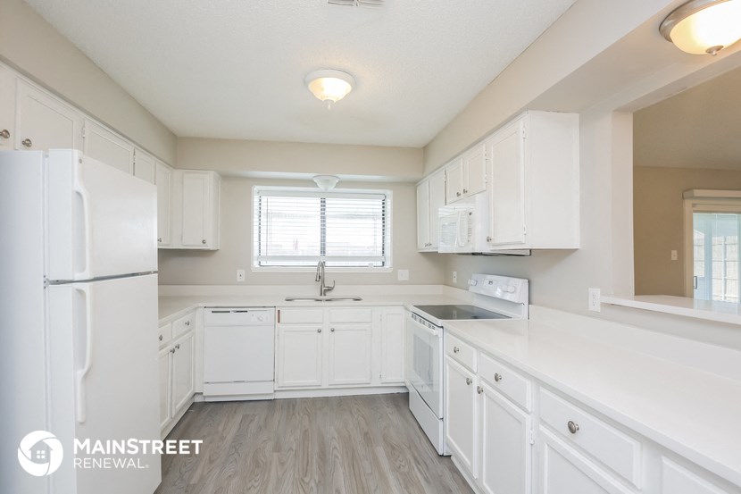 a white kitchen with white cabinets and a white refrigerator