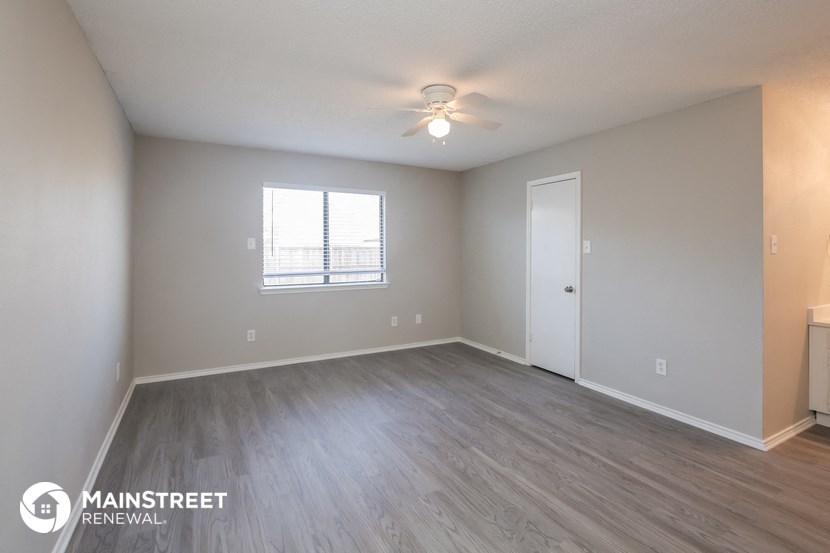 the spacious living room with wood flooring and a ceiling fan