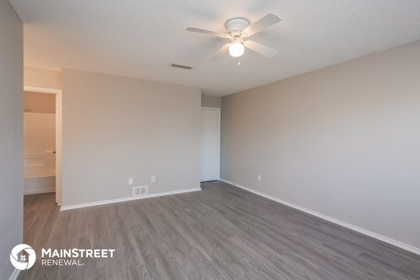 the spacious living room of an apartment with a ceiling fan