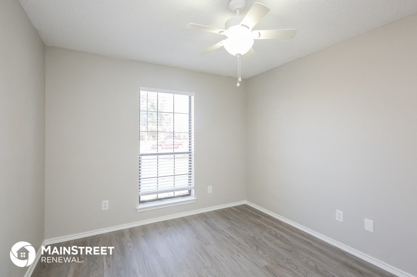 an empty room with a ceiling fan and a window