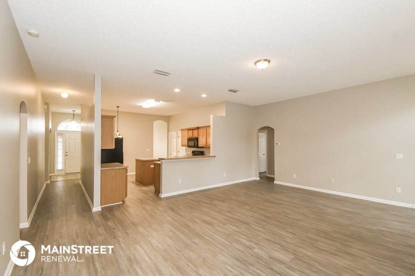 the living room and kitchen of an apartment with wood flooring