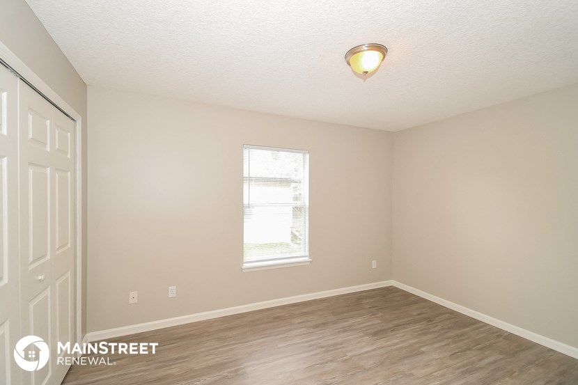 the interior of an empty room with wood flooring and a window