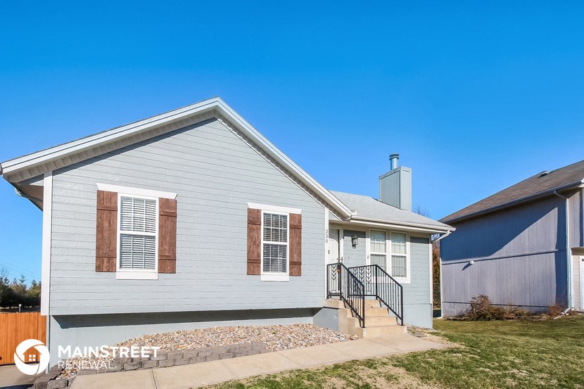 the front of a white house with a blue house next to it