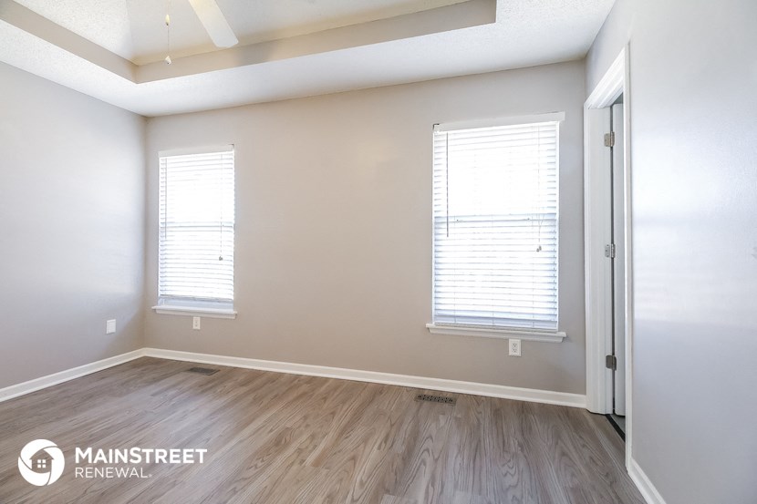 the living room of a new home with wood flooring and two windows