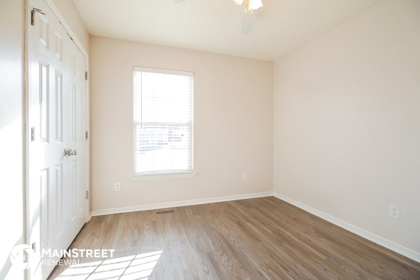 an empty room with white walls and a window and wooden floors