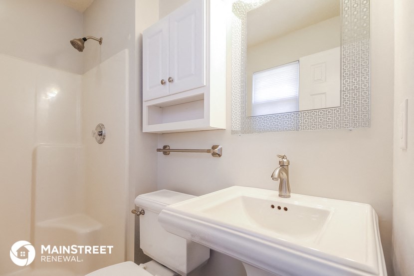a white bathroom with a sink and a toilet and a shower