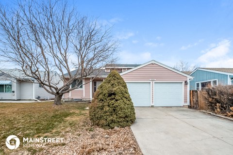 a blue and pink house with a driveway and a tree in front