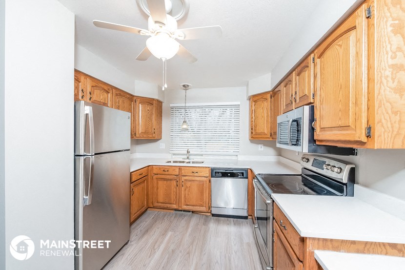 a kitchen with wooden cabinets and stainless steel appliances and a ceiling fan