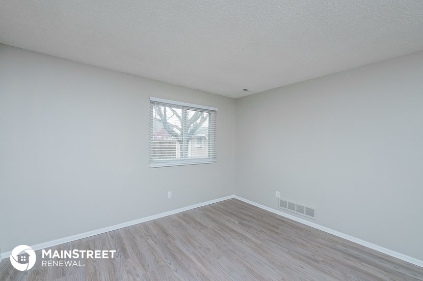 the spacious living room with wood flooring and white walls