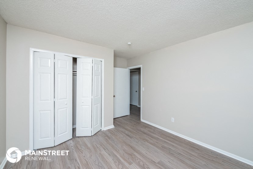 the living room of an apartment with white walls and wood flooring