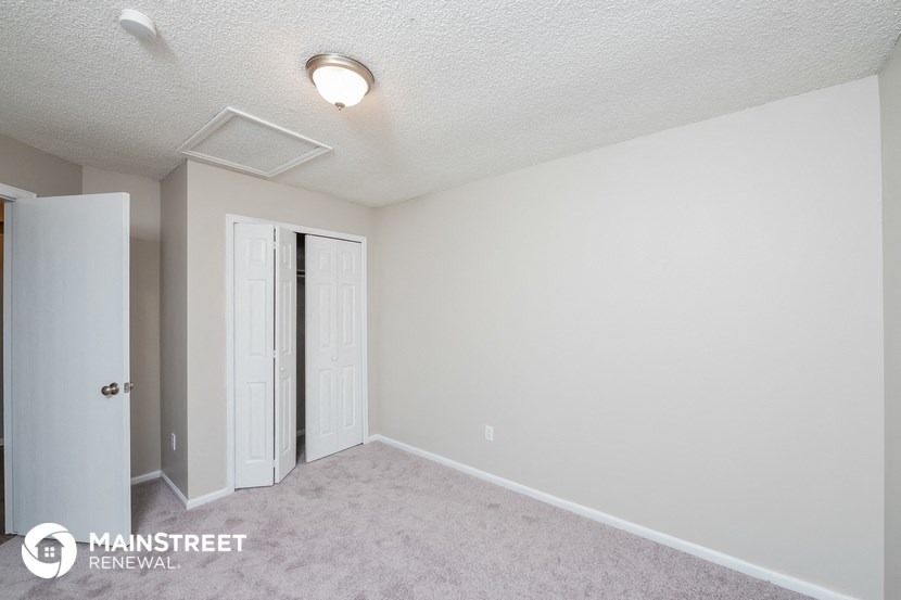 a bedroom with white walls and a door to a closet