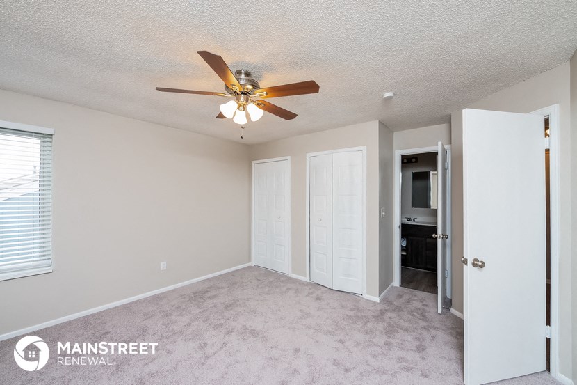 a bedroom with a ceiling fan and a door to the bathroom
