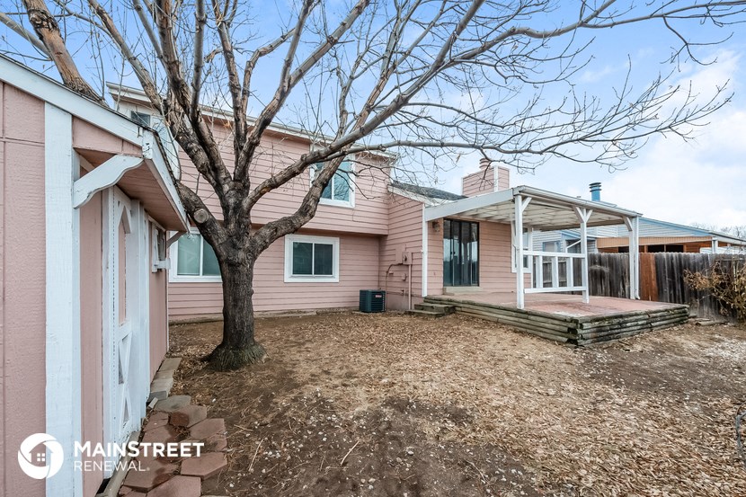 a pink house with a tree in the yard and a deck