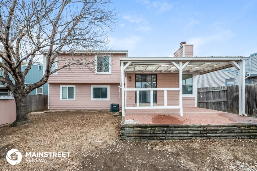 a pink house with a wooden deck and a tree