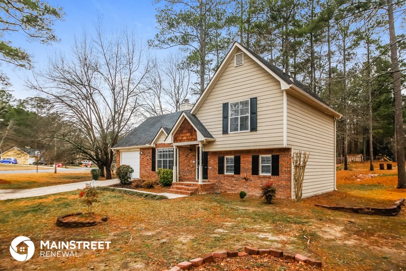 the front of a house with a lawn and trees