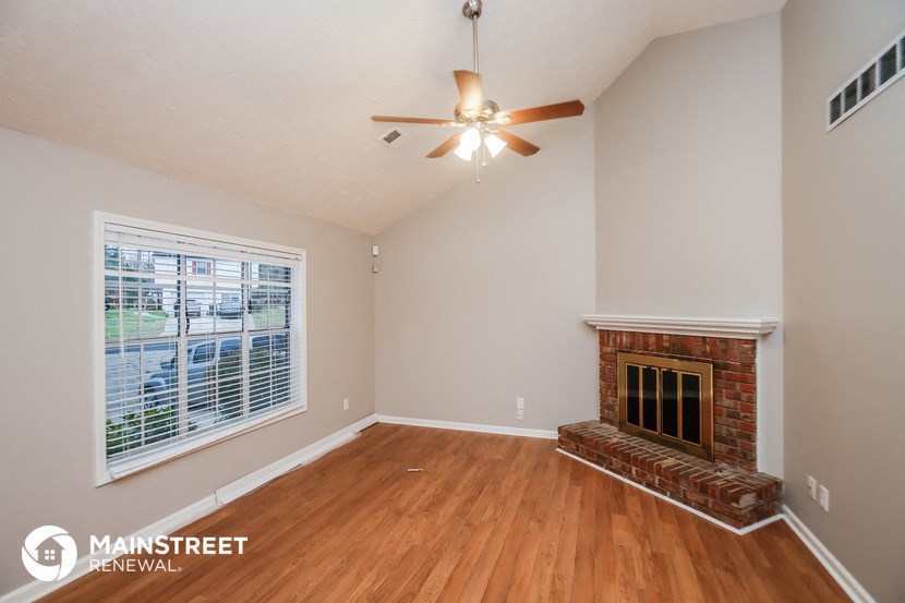 the living room with fireplace and ceiling fan