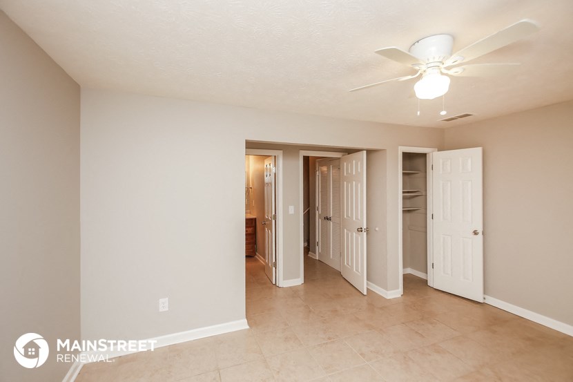 a living room with a ceiling fan and a hallway with a closet