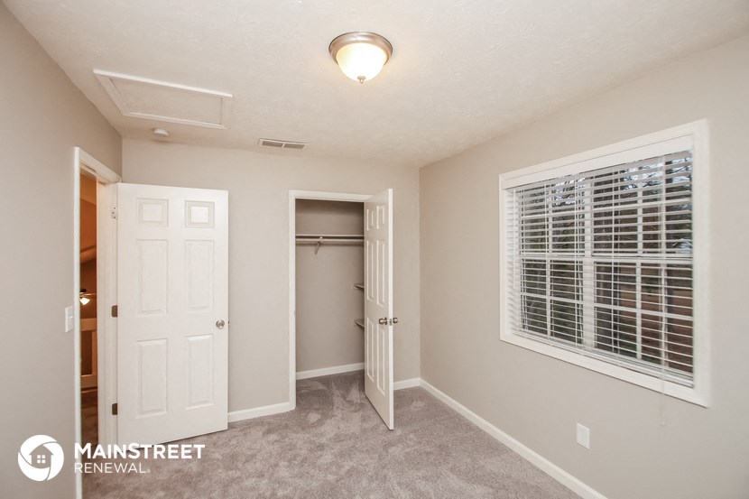 a bedroom with a door to a closet and a window