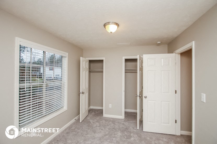 a bedroom with a door to a closet and a window with blinds