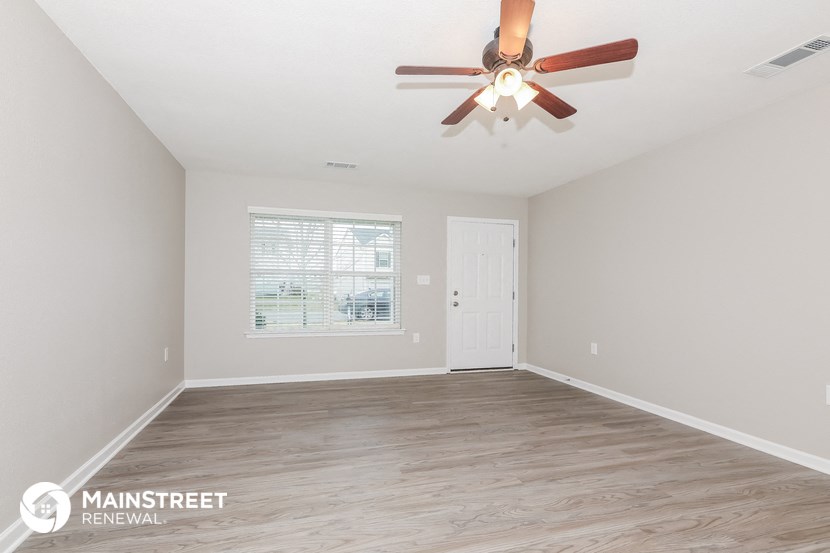 the spacious living room with a ceiling fan