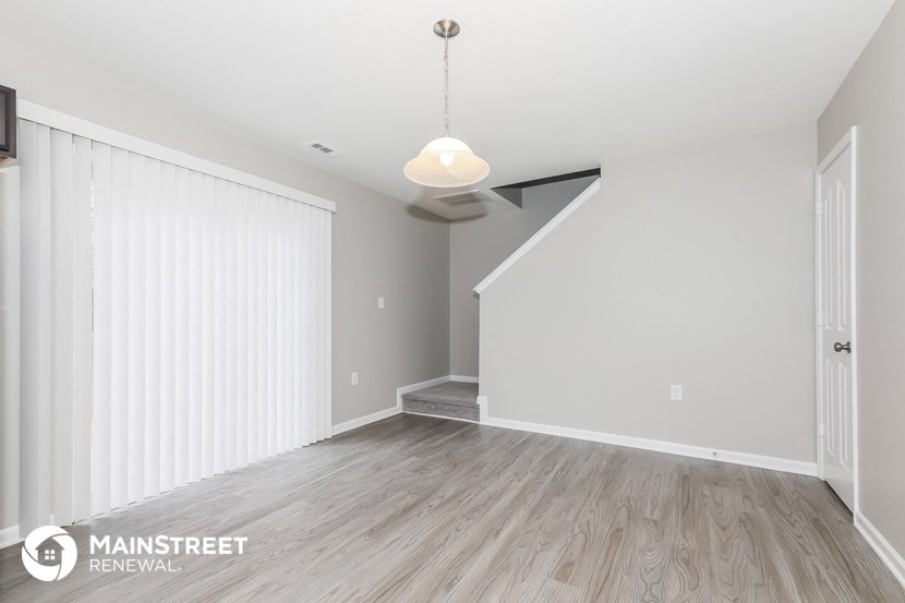 the living room and dining room of a renovated house with white walls and wood floors