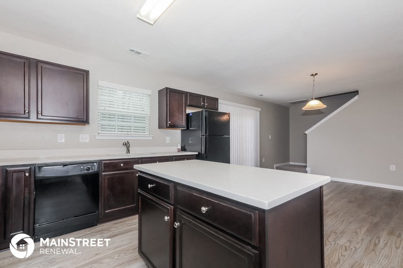 a kitchen with a white counter top and dark wood cabinets