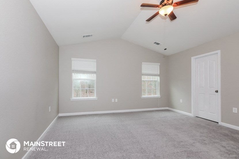 the master bedroom with carpeted flooring and a ceiling fan