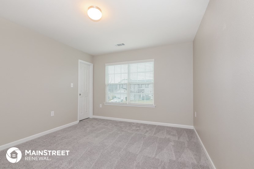 the spacious living room with carpeted flooring and a large window