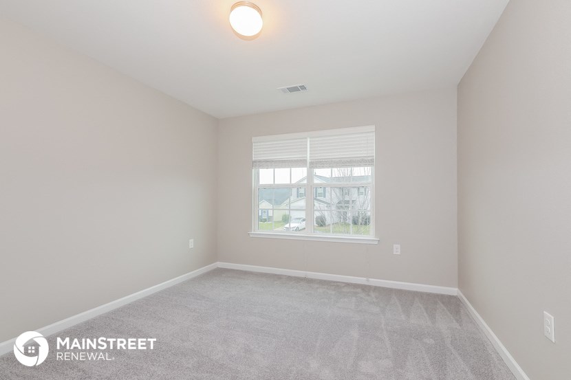 the spacious living room with a large window and carpeted flooring