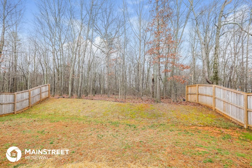 the backyard of the home has a large yard and a fence