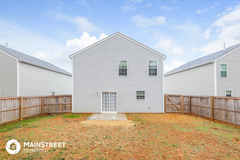 a backyard with a white house and a wooden fence