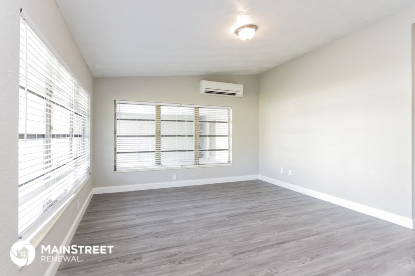 the spacious living room with a large window and wood flooring