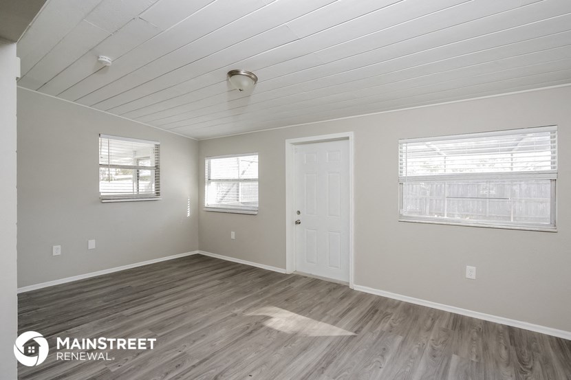 the spacious living room with wood flooring and a white door