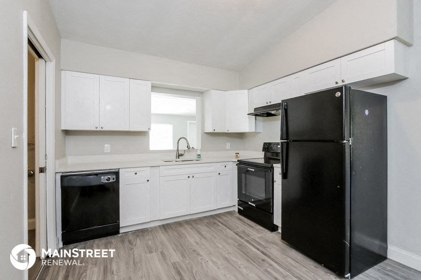 a white kitchen with black appliances and white cabinets