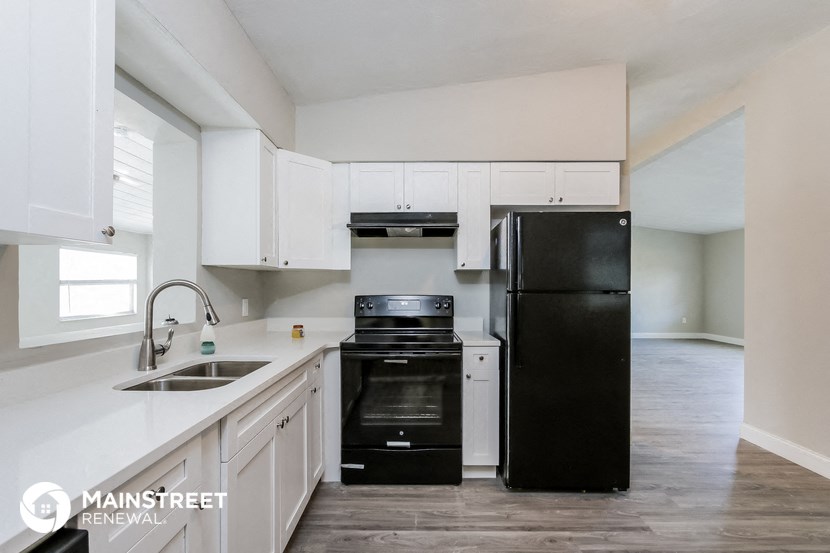 an empty kitchen with white cabinets and black appliances