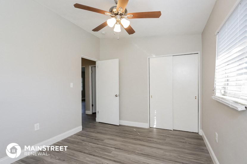 the spacious living room with ceiling fan and closet
